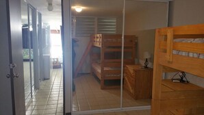 Ein Zimmer mit einem Etagenbett, einem kleinen Schreibtisch mit Lampe und einer Schiebetür zu einem Außenbereich.