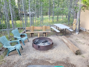 Fire pit with cut wood and a picnic table.