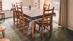 Una sala da pranzo con un tavolo grande, sedie in legno, un lampadario e vista attraverso una porta scorrevole in vetro.