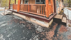 Una locanda con un portico in legno, un ingresso coperto e vista sulla foresta circostante.