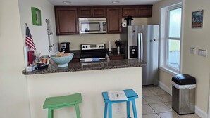 A kitchen with a microwave, stove, refrigerator, and a window. - 2 Bedroom, second row beach cottage .  (Cedar Island)