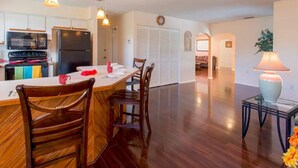 A spacious kitchen with wooden chairs, a dining table, and a modern refrigerator. - Waterfront Home With Pool (Port Richey)