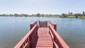 A wooden pier extending into a calm lake with a clear sky above. - Waterfront Home With Pool (Port Richey)