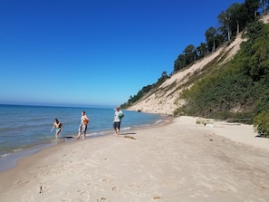 Enjoy a serene beach experience with access to the ocean and a tranquil grassy area with trees.