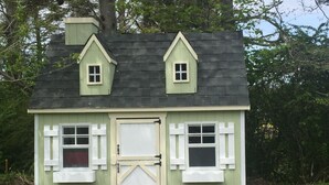 Une petite maison de plain-pied, dotée d’un toit à pignon et d’une porte centrale.