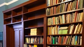 Una biblioteca amb prestatgeries de fusta plenes de llibres.