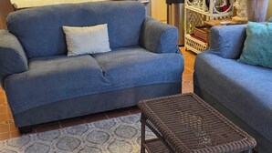 A living room with a blue sofa, a wicker coffee table, and a patterned rug.