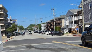 A street with buildings, parked cars, and a clear blue sky.