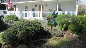 Una casa de dos pisos con un porche, una bandera y una escultura de pájaro.
