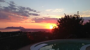 Una piscina con vistas a un atardecer sobre un cuerpo de agua y montañas.