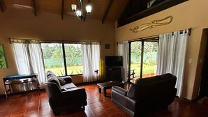 Amplia sala de estar con un televisor grande, asientos cómodos y vistas al exterior.