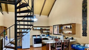 Una cocina amplia con una isla central, un comedor con sillas de madera y una escalera de caracol.