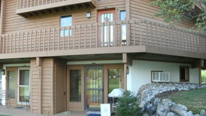 A two-story building with a flat roof and a stone retaining wall.