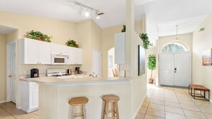 A kitchen with white cabinets, a microwave, a gas stove, and two wooden stools. - Last-Minute-Rates  . LET YOUR DREAMS COME TRUE - King Bed, Gas Grill & Game Room (Davenport)