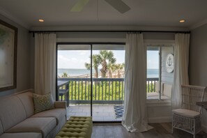 A room with a balcony overlooking the ocean, a sofa, a chair, and a small table. - Beachfront condo as featured on HGTV! (Tybee Island)