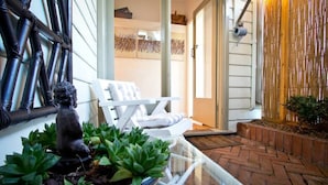 Un patio con una silla blanca, una planta en maceta y una estatua decorativa.