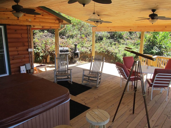 Relax on the deck with a hot tub, grill, and telescope, surrounded by lush greenery.