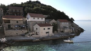 Ein Küstendorf mit Steinhäusern, klarem Wasser und einem Boot, das an der Küste liegt.