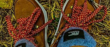 A pair of brown shoes with red and white checkered laces and a blue fleece lining.