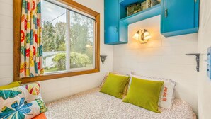 Un dormitorio con una cama, cortinas coloridas, un ventanal y armarios azules.