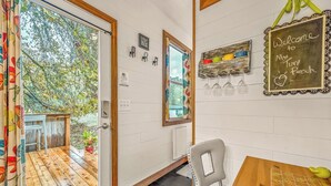 Una habitación acogedora con una puerta de madera que da a un balcón, una mesita con un posavasos y un letrero de pizarra dando la bienvenida a los huéspedes.