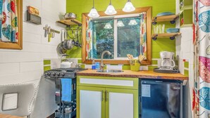 Cocina compacta con estufa a gas, lavamanos y cafetera.