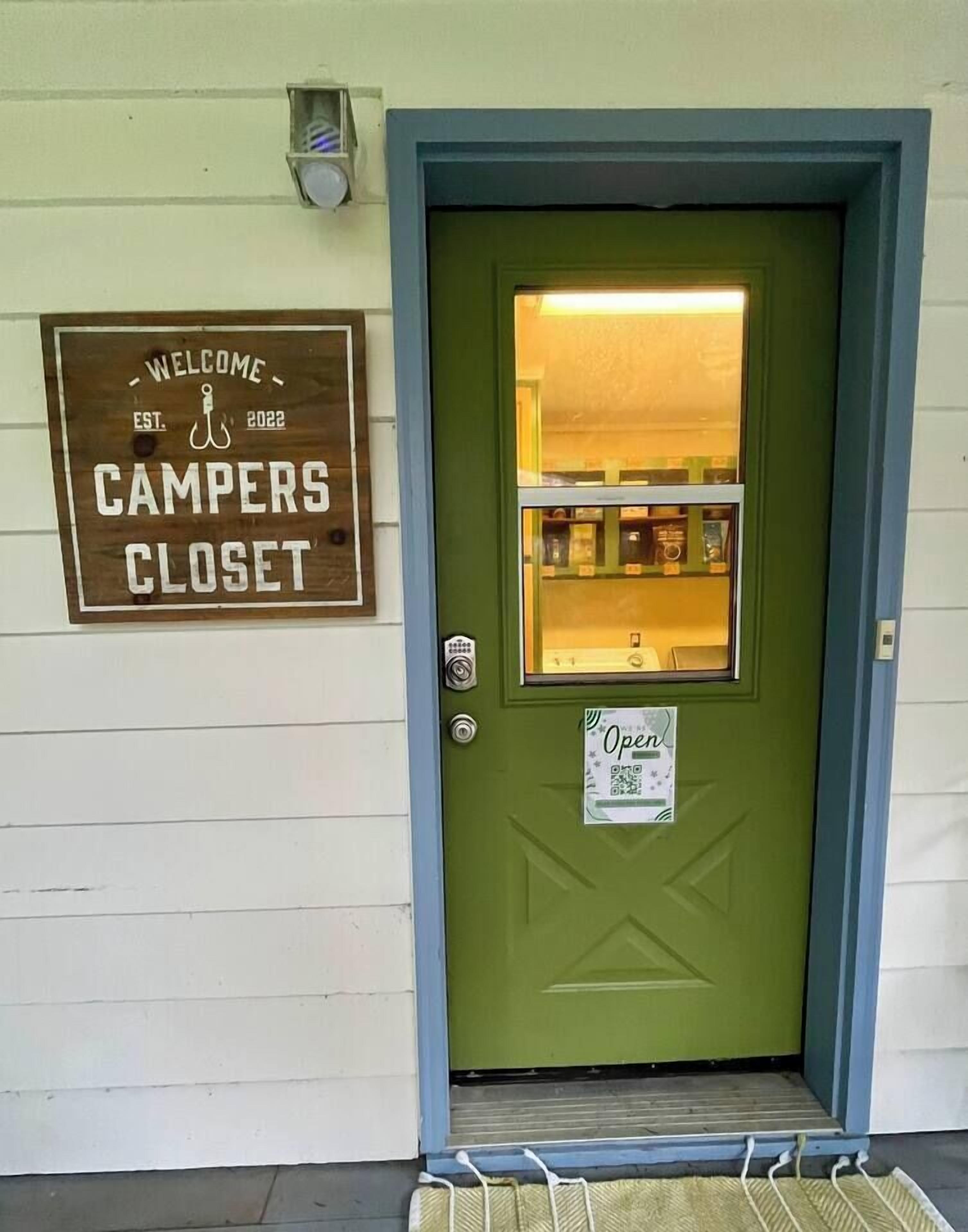 A green door with a sign above it that reads "Welcome Campers Closet."