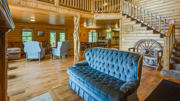 Un vaste espace de vie avec un canapé bleu, un plancher en bois, un escalier en bois et un ventilateur de plafond.
