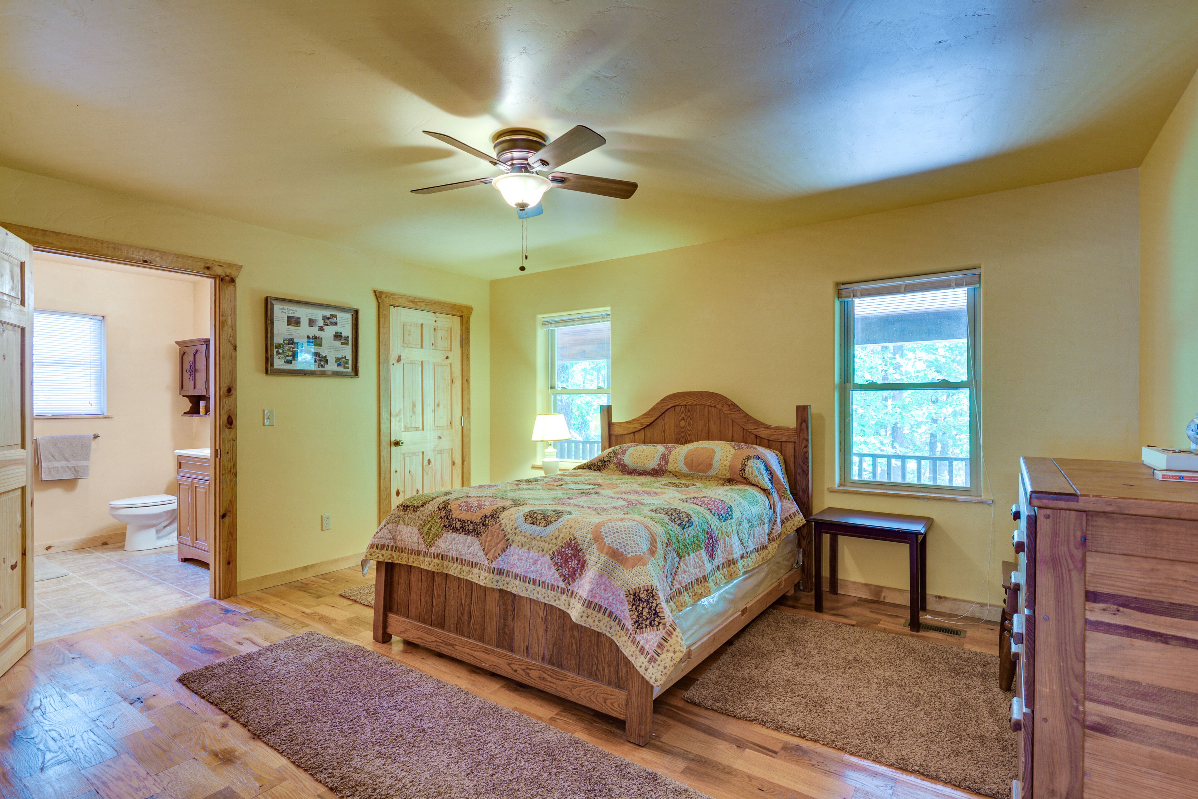 A bedroom with a wooden bed, a ceiling fan, a wooden dresser, and a window.