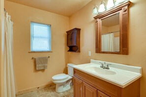 Een badkamer met toilet, wastafel, spiegel en raam.