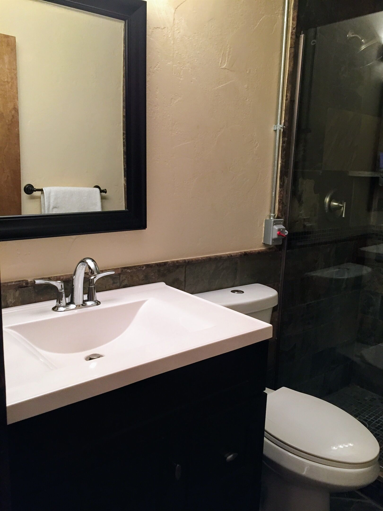 Un baño con lavamanos blanco, un espejo y un inodoro.