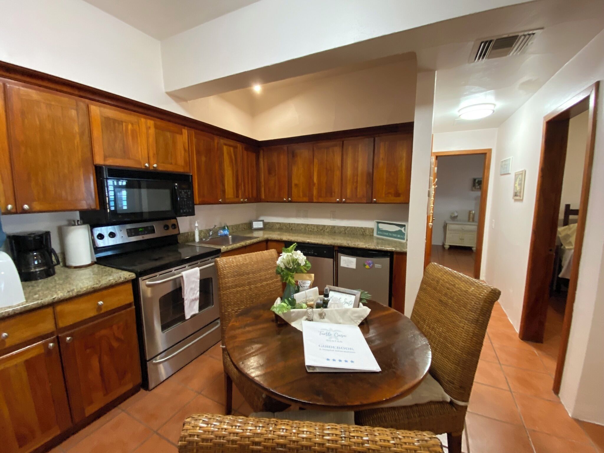A kitchen with wooden cabinets, a microwave, stove, and a dining table with chairs.
