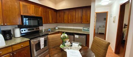 A kitchen with wooden cabinets, a microwave, stove, and a dining table with chairs.