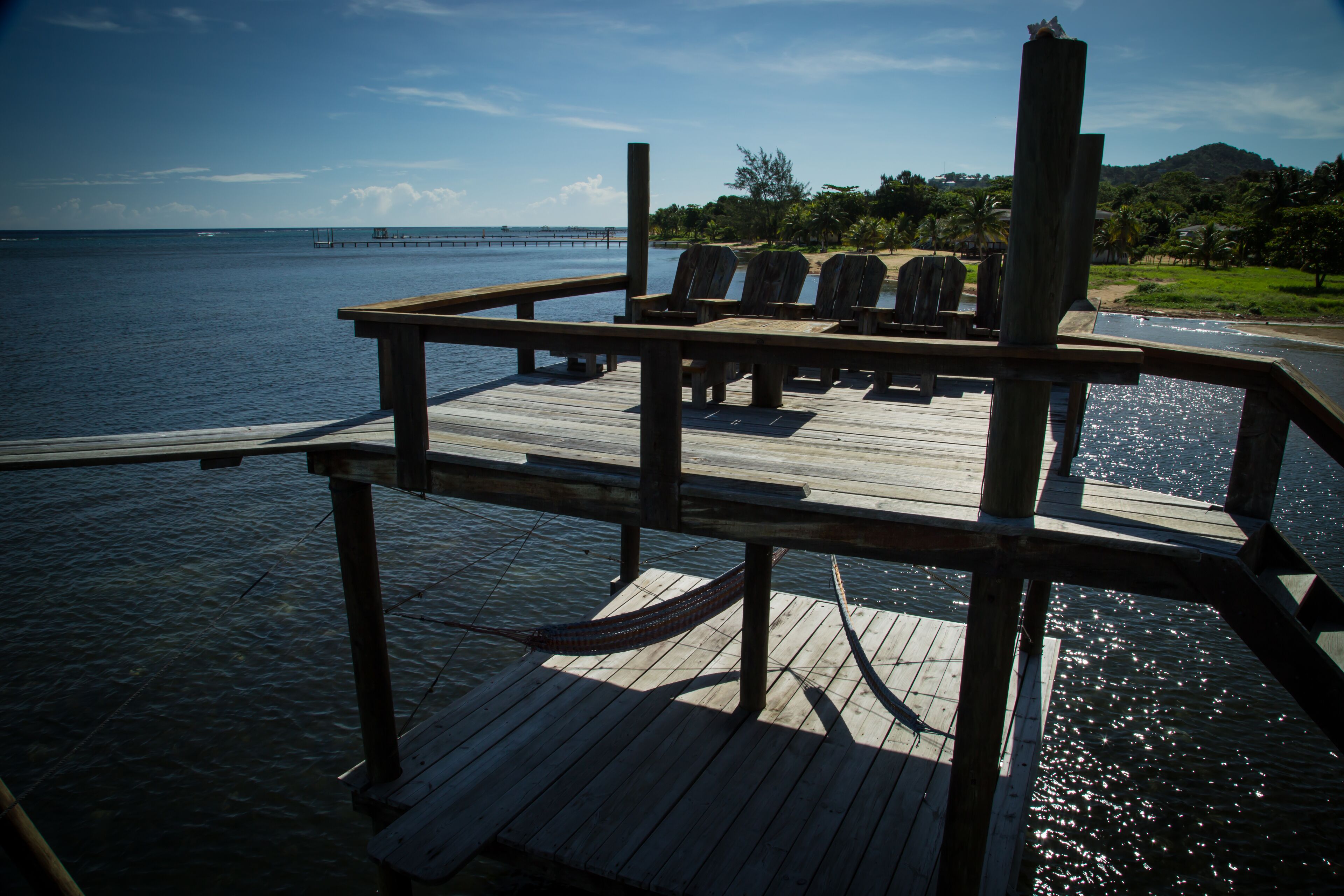 Een houten terras met stoelen en een tafel, uitkijkend op een waterpartij.