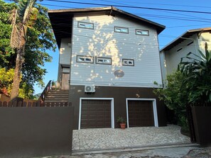 En tvåvåningsbyggnad med ett garage, en entré med stenläggning och en liten krukväxt.