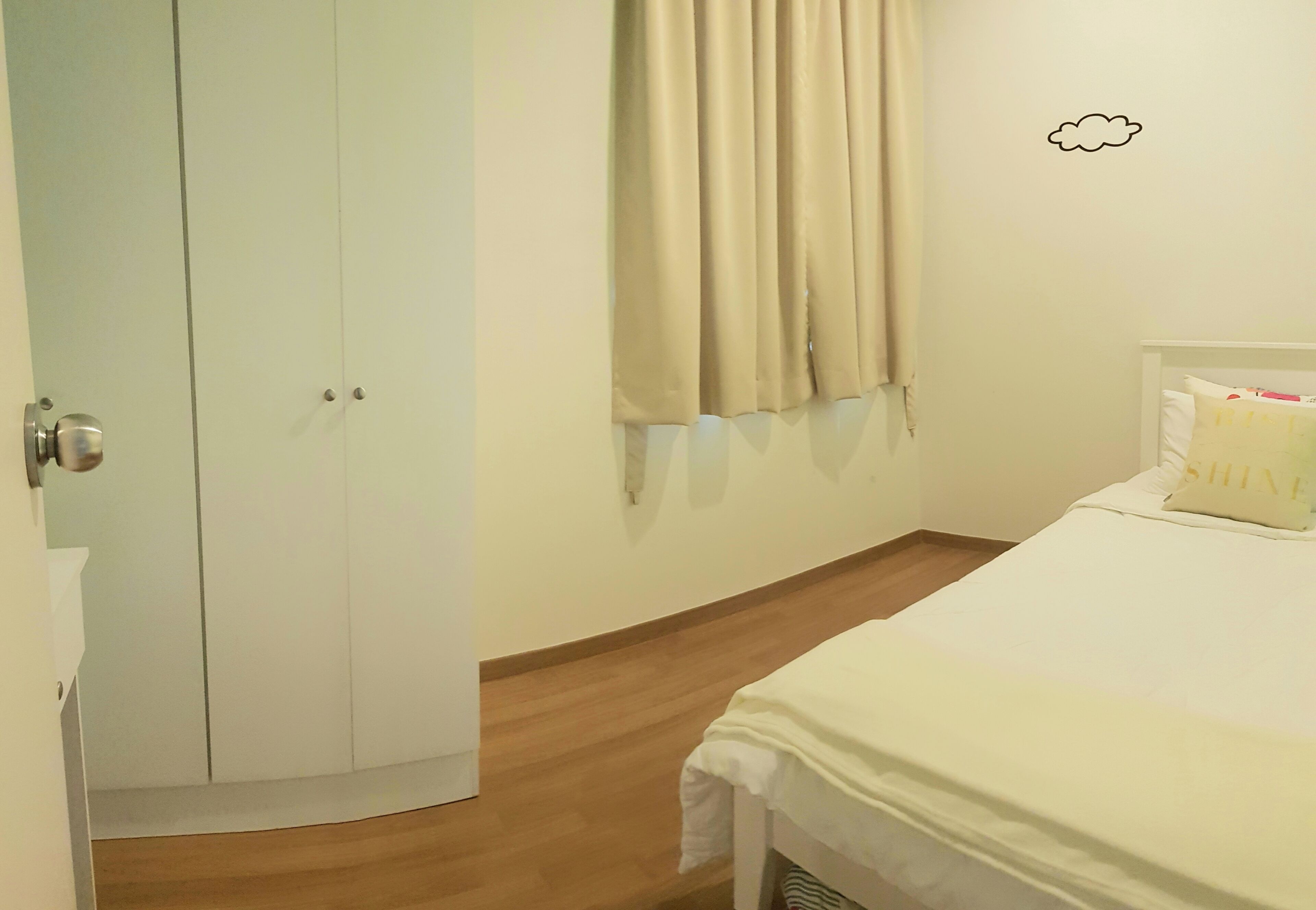 A bedroom with a bed, a wardrobe, and a window with curtains.