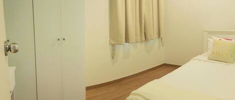 A bedroom with a bed, a wardrobe, and a window with curtains.