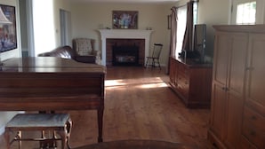 A spacious living room with a fireplace, wooden furniture, and a television. - Oceanfront Beach House In Plymouth (Plymouth)