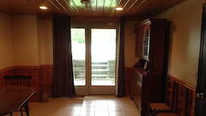 A room with a wooden ceiling, a dining table with chairs, a kitchen area with cabinets, and a sliding glass door leading to an outdoor area. - Oceanfront Beach House In Plymouth (Plymouth)