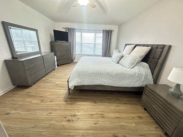 Une chambre à coucher avec un lit, une commode, une télévision et des rideaux.