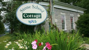 Un cartel para Stone School Cottage, con un edificio de piedra al fondo.