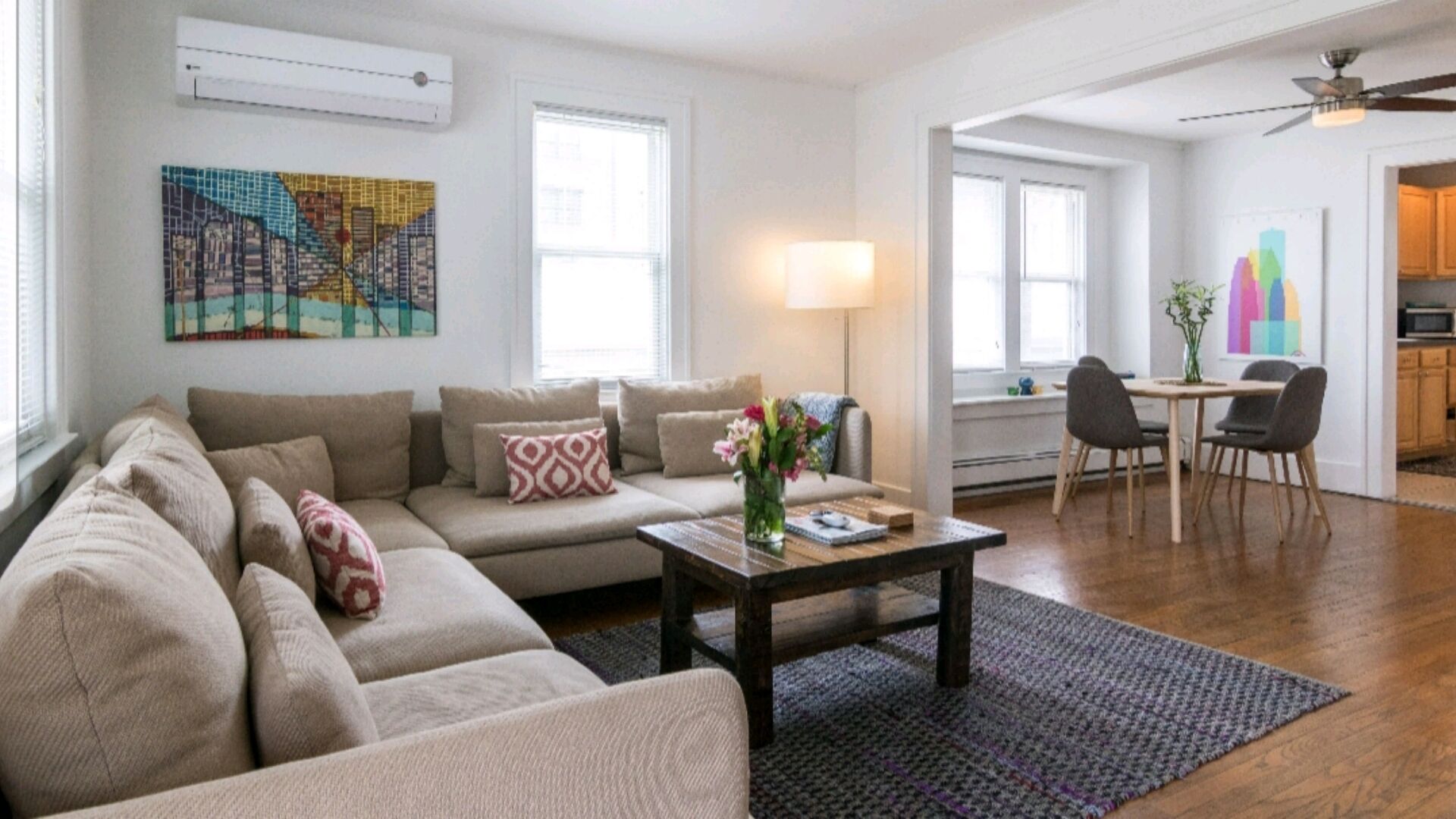 A living room with a beige sofa, a coffee table, and a dining area with a table and chairs.