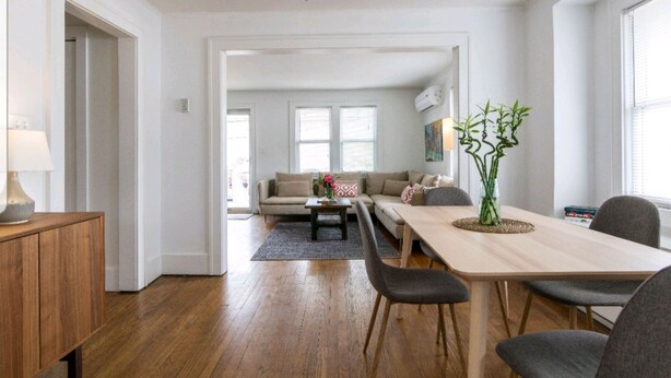 Een moderne woonkamer met een houten eettafel, grijze banken en een salontafel.