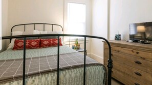 Cozy retreat with a comfortable bed, dresser, and TV.