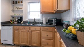 Compact kitchen with a window, sink, dishwasher, microwave, and coffee maker.