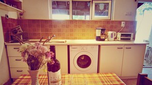 A kitchen with a washing machine, a wine bottle, and two wine glasses on a checkered tablecloth. - Clean Nature & Beautiful View (Balchik)