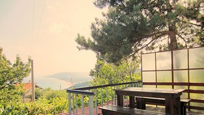 A stone patio with a wooden table and benches, overlooking a vineyard and distant hills. - Clean Nature & Beautiful View (Balchik)