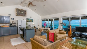 A spacious living area with a kitchen, dining area, and a large window overlooking the ocean. - Bonefish Bella Vista - Beachfront Retreat, Tropical Garden & Natural Ocean Pool (Georgetown)