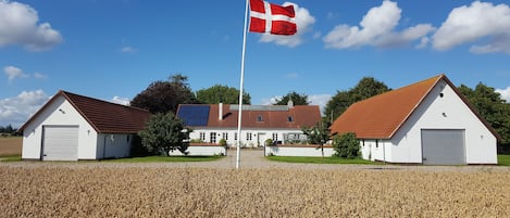 En bygning med to lader, en flagstang med flag, og en mark i forgrunden.