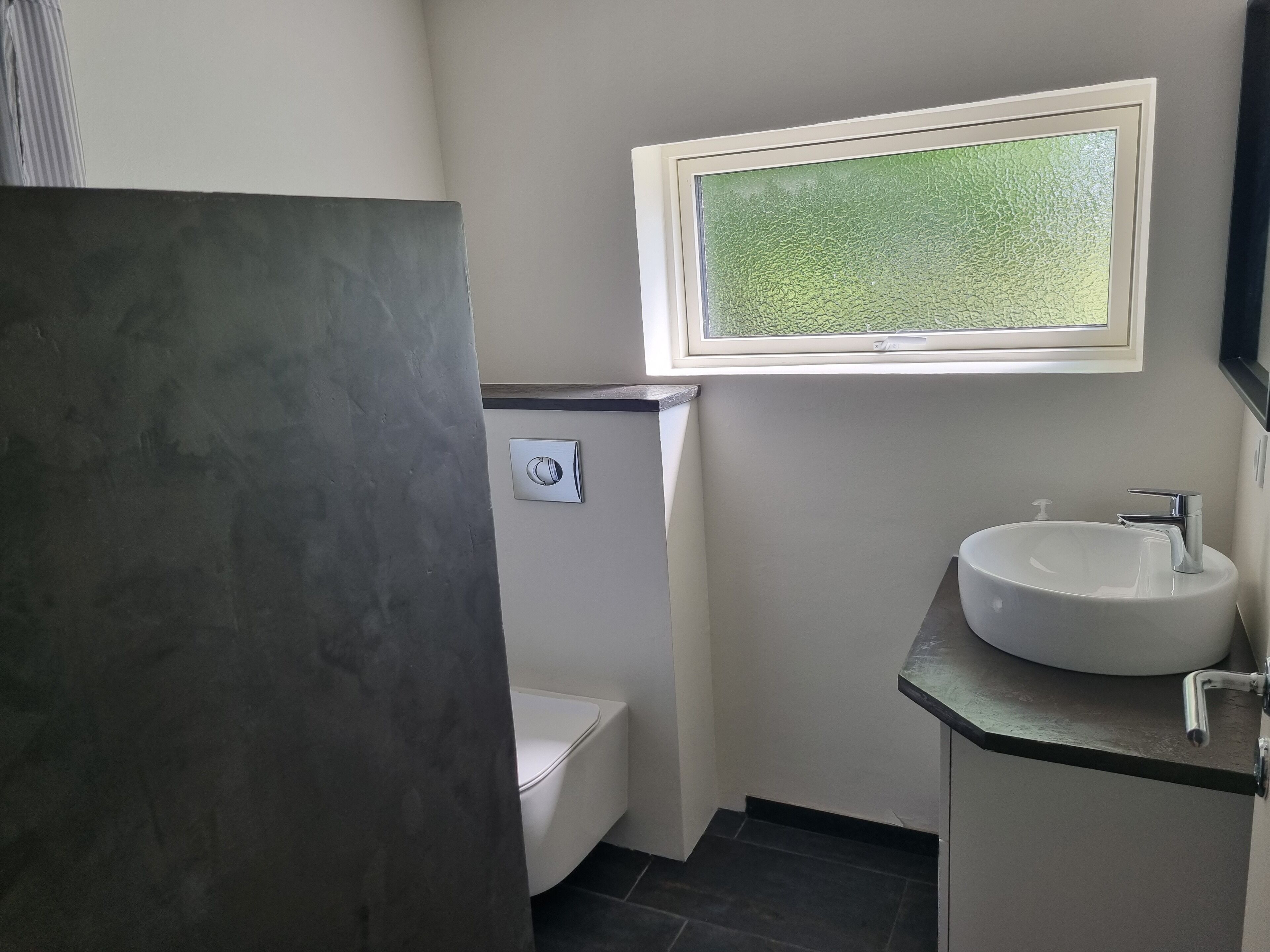 Un baño pequeño con inodoro, lavamanos y ventana.